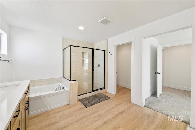 full bath with recessed lighting, wood finished floors, vanity, a bath, and a stall shower