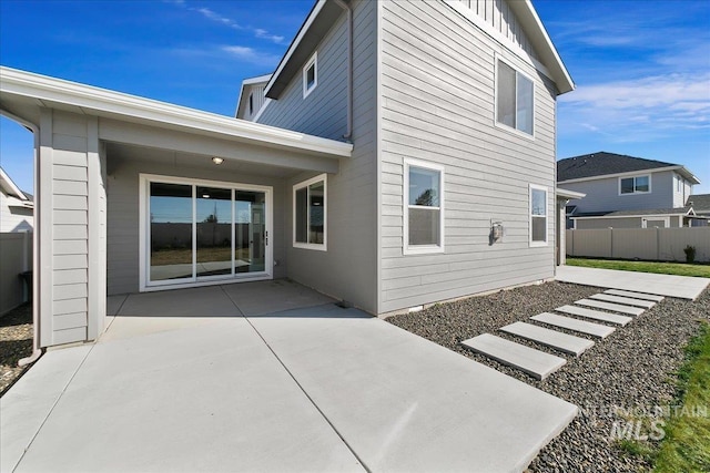 back of property featuring board and batten siding, a patio, and fence
