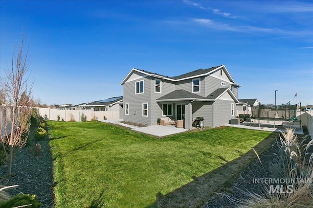 back of property with a yard, a trampoline, a fenced backyard, and a patio