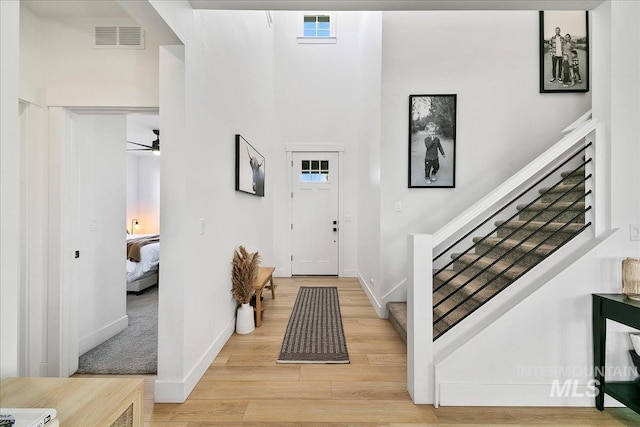 entrance foyer with baseboards, visible vents, light wood-style floors, a ceiling fan, and stairway
