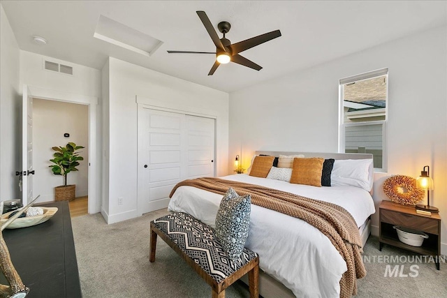 bedroom with attic access, light carpet, visible vents, a ceiling fan, and a closet