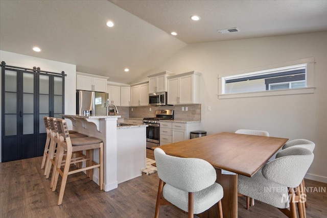7682 W Itasco Dr, Boise, ID 83709 - dining room featuring lofted ceiling, dark wood-type flooring, recessed lighting, and a barn door