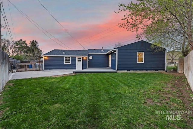 5805 W Robertson Dr, Boise, ID 83709 - back of property at dusk with a wooden deck, a lawn, and a fenced backyard