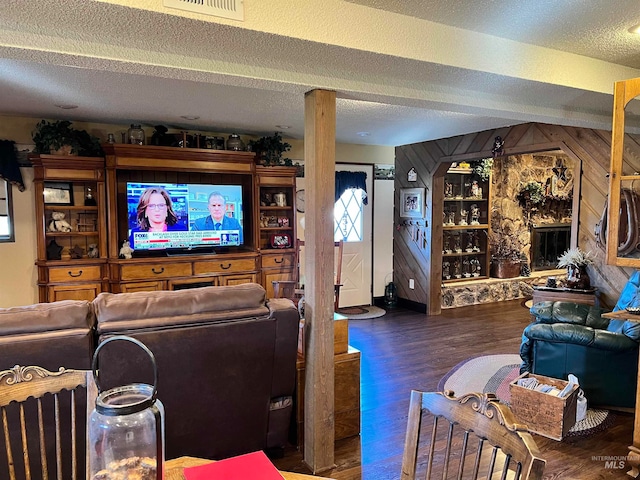 living room featuring wood walls, dark wood-type flooring, a textured ceiling, and a fireplace