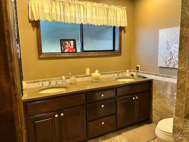 bathroom with double sink, tile walls, tile flooring, toilet, and large vanity