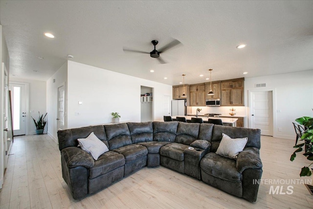 living area featuring recessed lighting, light wood-type flooring, visible vents, and a ceiling fan