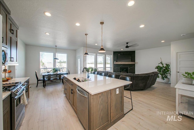 kitchen with recessed lighting, a ceiling fan, a sink, a fireplace, and appliances with stainless steel finishes