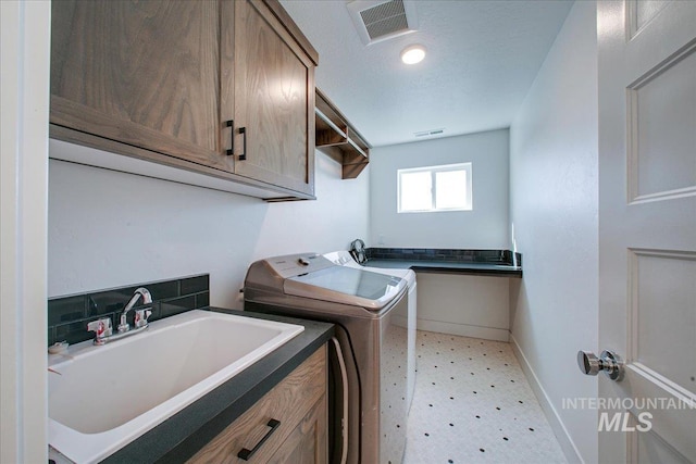 clothes washing area with a sink, light floors, cabinet space, baseboards, and visible vents