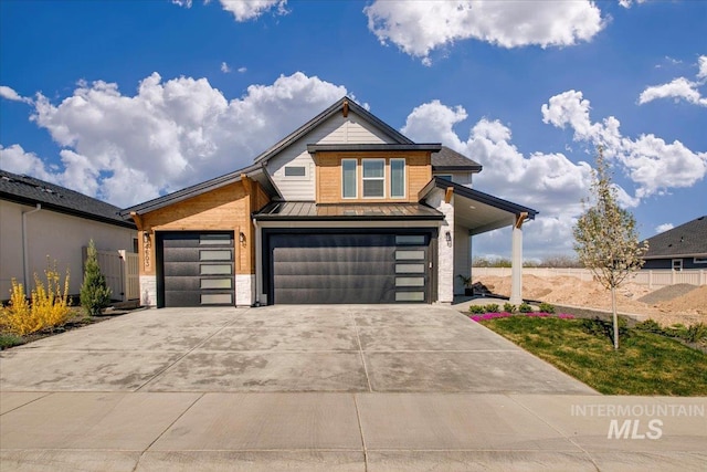 contemporary home with metal roof, a standing seam roof, driveway, stone siding, and a garage