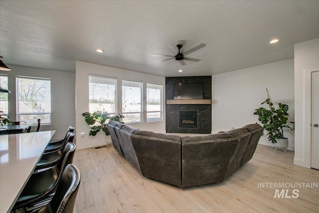 living room with a fireplace, light wood finished floors, ceiling fan, and recessed lighting