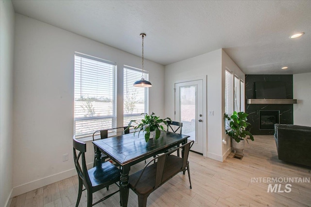 dining space with recessed lighting, a premium fireplace, light wood-style floors, and baseboards