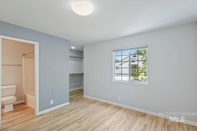 2285 S Challenger Unit 201, Boise, ID 83705 - unfurnished bedroom featuring wood finished floors, a closet, baseboards, ensuite bath, and a walk in closet