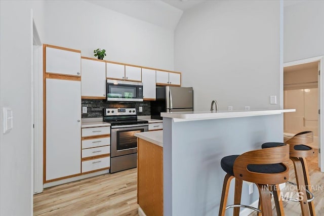 2285 S Challenger Unit 201, Boise, ID 83705 - kitchen with stainless steel appliances, a breakfast bar area, decorative backsplash, vaulted ceiling, and light countertops