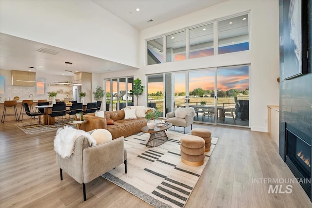 12975 Shasta Daisy Way, Nampa, ID 83686 - living room with light wood-style flooring, a glass covered fireplace, a towering ceiling, recessed lighting, and baseboards