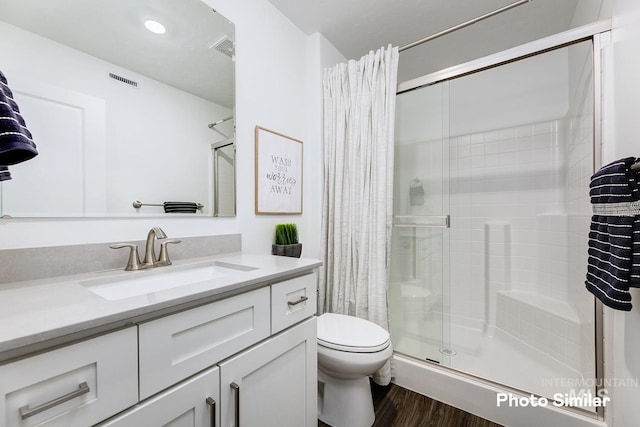 bathroom featuring an enclosed shower, vanity, toilet, and wood-type flooring