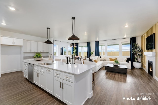 kitchen featuring sink, dark hardwood / wood-style floors, pendant lighting, a center island with sink, and white cabinets