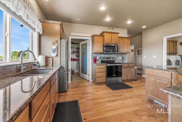 10395 Willis Rd, Middleton, ID 83644 - kitchen featuring light wood finished floors, a sink, washer and clothes dryer, tasteful backsplash, and appliances with stainless steel finishes
