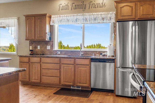 10395 Willis Rd, Middleton, ID 83644 - kitchen featuring a sink, decorative backsplash, dark stone counters, and appliances with stainless steel finishes