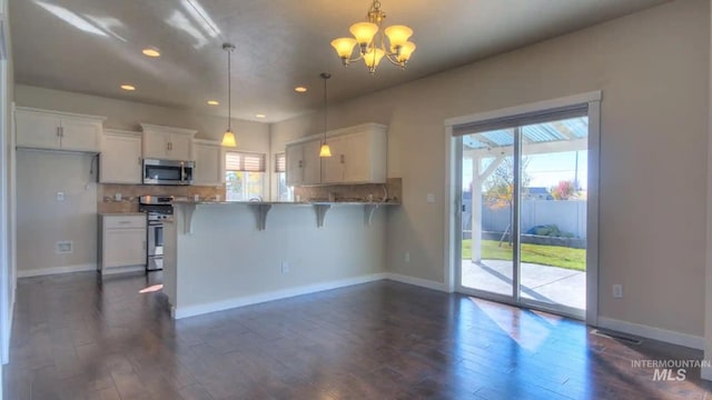 kitchen featuring white cabinets, appliances with stainless steel finishes, dark wood-style flooring, an inviting chandelier, and backsplash