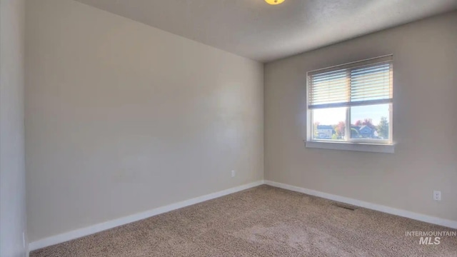 spare room with carpet flooring, visible vents, and baseboards