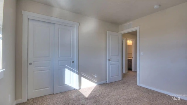 unfurnished bedroom with light carpet, visible vents, baseboards, and a closet