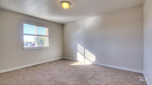 unfurnished room featuring a textured ceiling, carpet flooring, visible vents, and baseboards