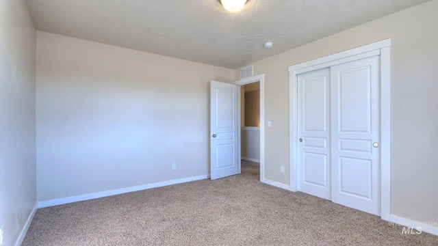 unfurnished bedroom featuring light carpet, visible vents, baseboards, and a closet