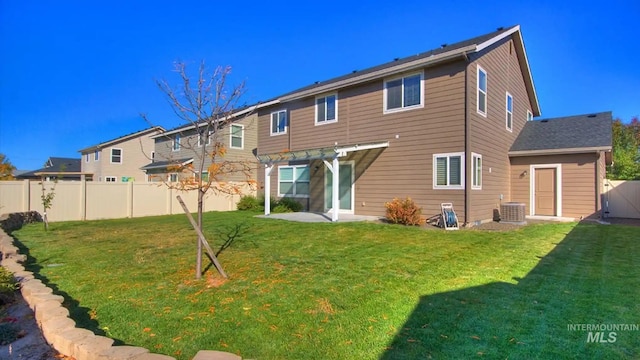 back of house with central air condition unit, fence, a lawn, and a patio