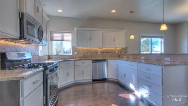 kitchen with stainless steel appliances, a peninsula, backsplash, and white cabinetry