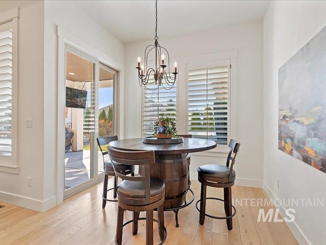 dining room with an inviting chandelier, light wood-style flooring, and baseboards