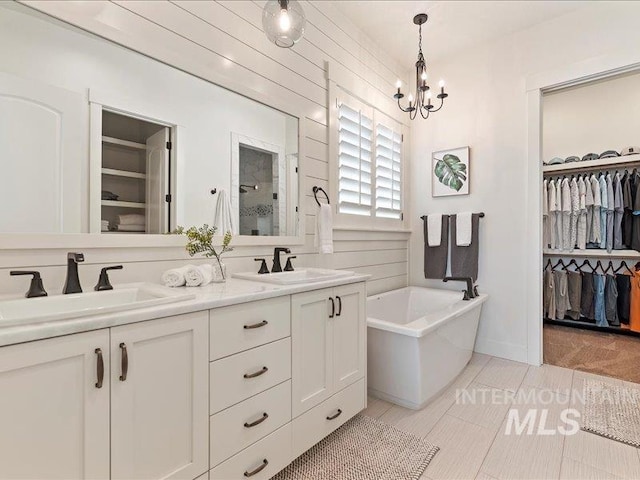 full bath featuring a sink, a walk in closet, and a freestanding bath