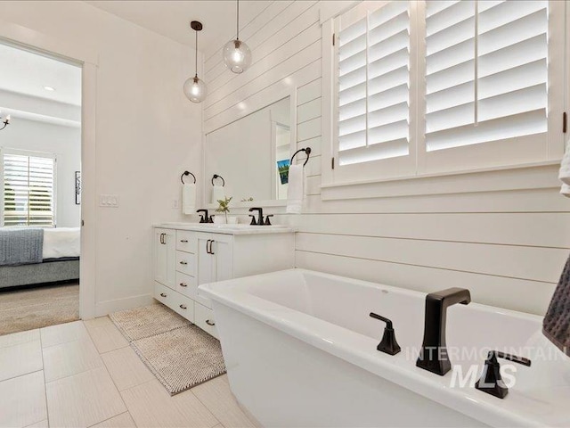 ensuite bathroom with double vanity, ensuite bath, a sink, and a washtub