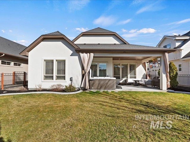 rear view of property featuring fence, stucco siding, a hot tub, a patio area, and an outdoor hangout area