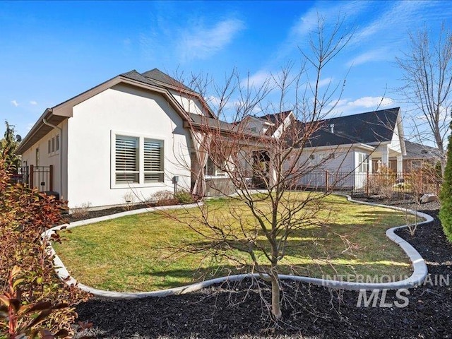 exterior space with a lawn, fence, and stucco siding