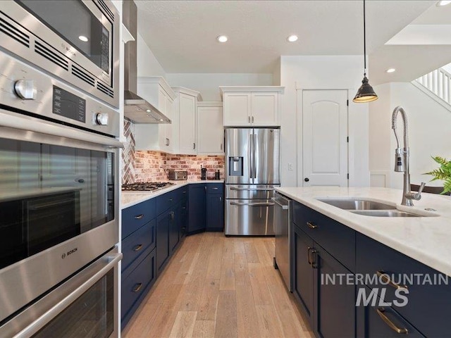 kitchen with blue cabinetry, a sink, stainless steel appliances, light countertops, and white cabinetry