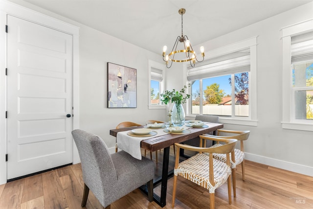 dining area with light wood finished floors, a notable chandelier, and baseboards