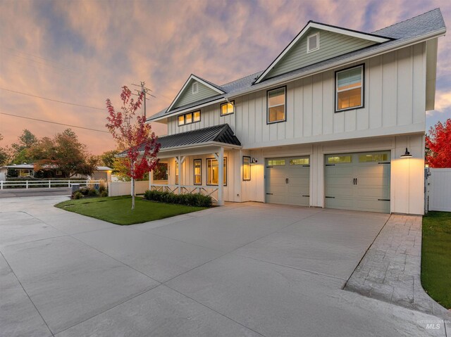view of front facade with driveway, board and batten siding, a garage, a standing seam roof, and fence