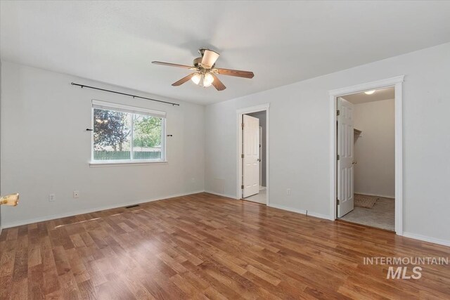 1600 Peregrine, Mountain Home, ID 83647 - unfurnished bedroom featuring wood finished floors, baseboards, connected bathroom, a walk in closet, and a ceiling fan