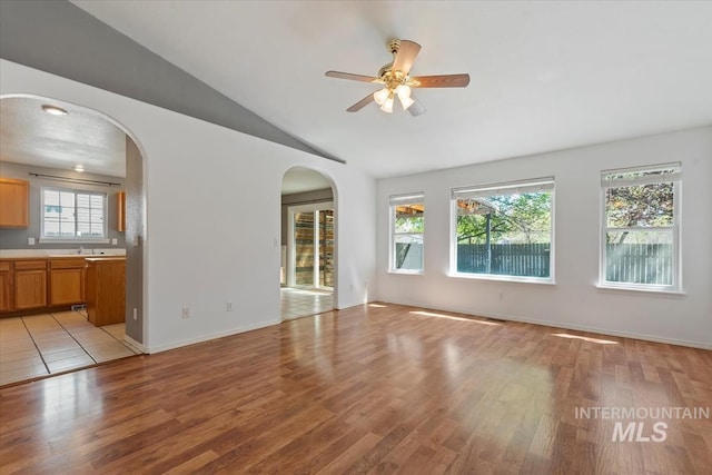 1600 Peregrine, Mountain Home, ID 83647 - unfurnished living room featuring arched walkways, light wood-style floors, lofted ceiling, a ceiling fan, and baseboards