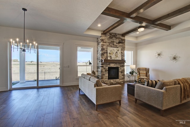 living room featuring beamed ceiling, a fireplace, dark hardwood / wood-style floors, and a chandelier