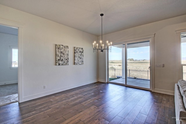 unfurnished dining area with dark hardwood / wood-style flooring and an inviting chandelier