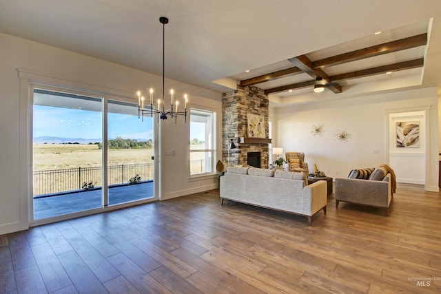 living room featuring a stone fireplace, hardwood / wood-style flooring, beam ceiling, coffered ceiling, and an inviting chandelier