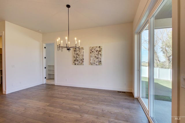 unfurnished dining area with hardwood / wood-style flooring and a chandelier