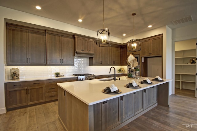 kitchen featuring dark hardwood / wood-style floors, an island with sink, decorative light fixtures, and sink