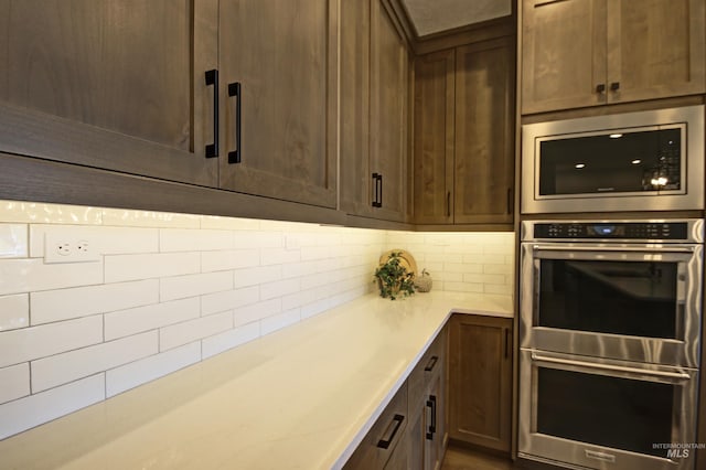 kitchen with built in microwave, dark brown cabinetry, double oven, and decorative backsplash