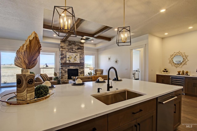 kitchen featuring wine cooler, decorative light fixtures, sink, and a stone fireplace