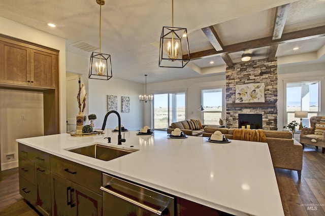 kitchen featuring sink, stainless steel dishwasher, dark hardwood / wood-style floors, beamed ceiling, and a fireplace