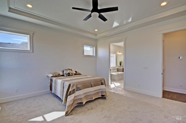 bedroom featuring ceiling fan, connected bathroom, a raised ceiling, and light carpet