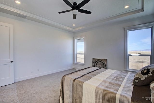 bedroom featuring ceiling fan, light colored carpet, and a tray ceiling