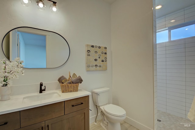 bathroom with vanity, a tile shower, and toilet